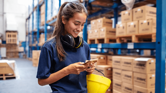 female trainee at warehouse interacting with smartphone